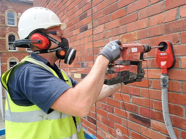 Brick-Tie employee drilling with dust suppression, eye protection and face fit tested dust mask and 