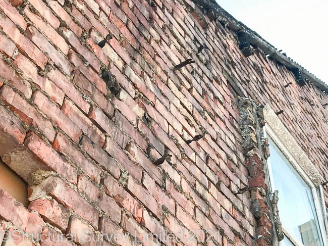 Close up of a collapsed gable wall showing the cause is severe cavity wall tie corrosion.