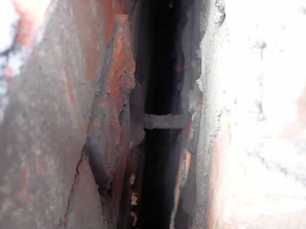 A cavity view of a metal wall tie which appears intact but has failed due to corrosion