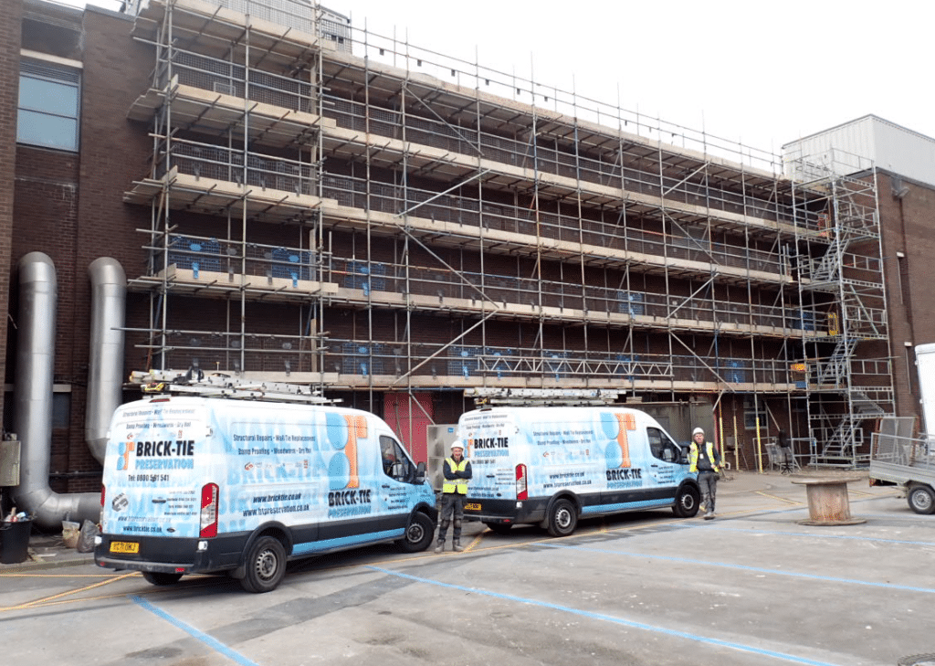 Two brick-tie vans at work installing retro-fit masonry movement joints and remedial wall ties